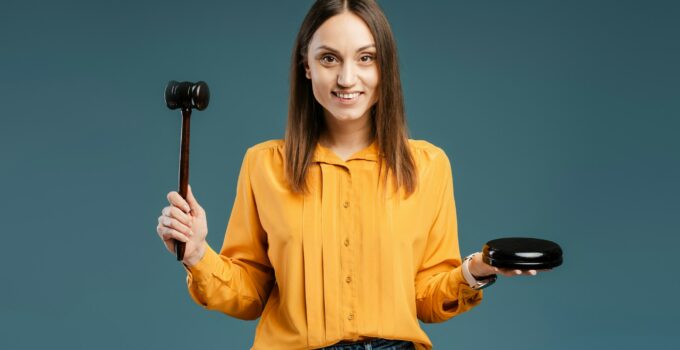 Smiling woman judge holding gavel to bang on sounding block in studio