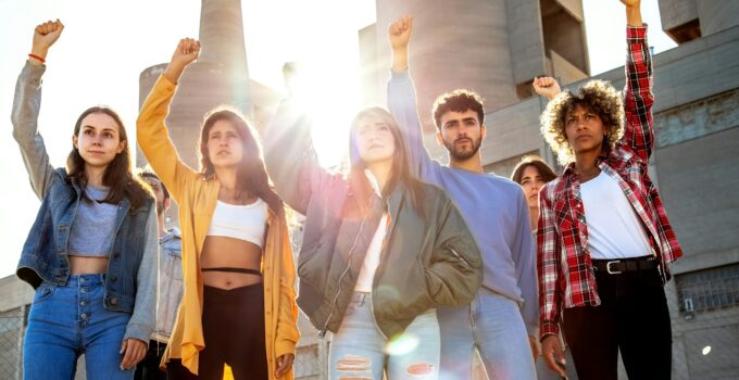 Group of multiracial protesters with fists raised up in the air. Activists protesting on the street.